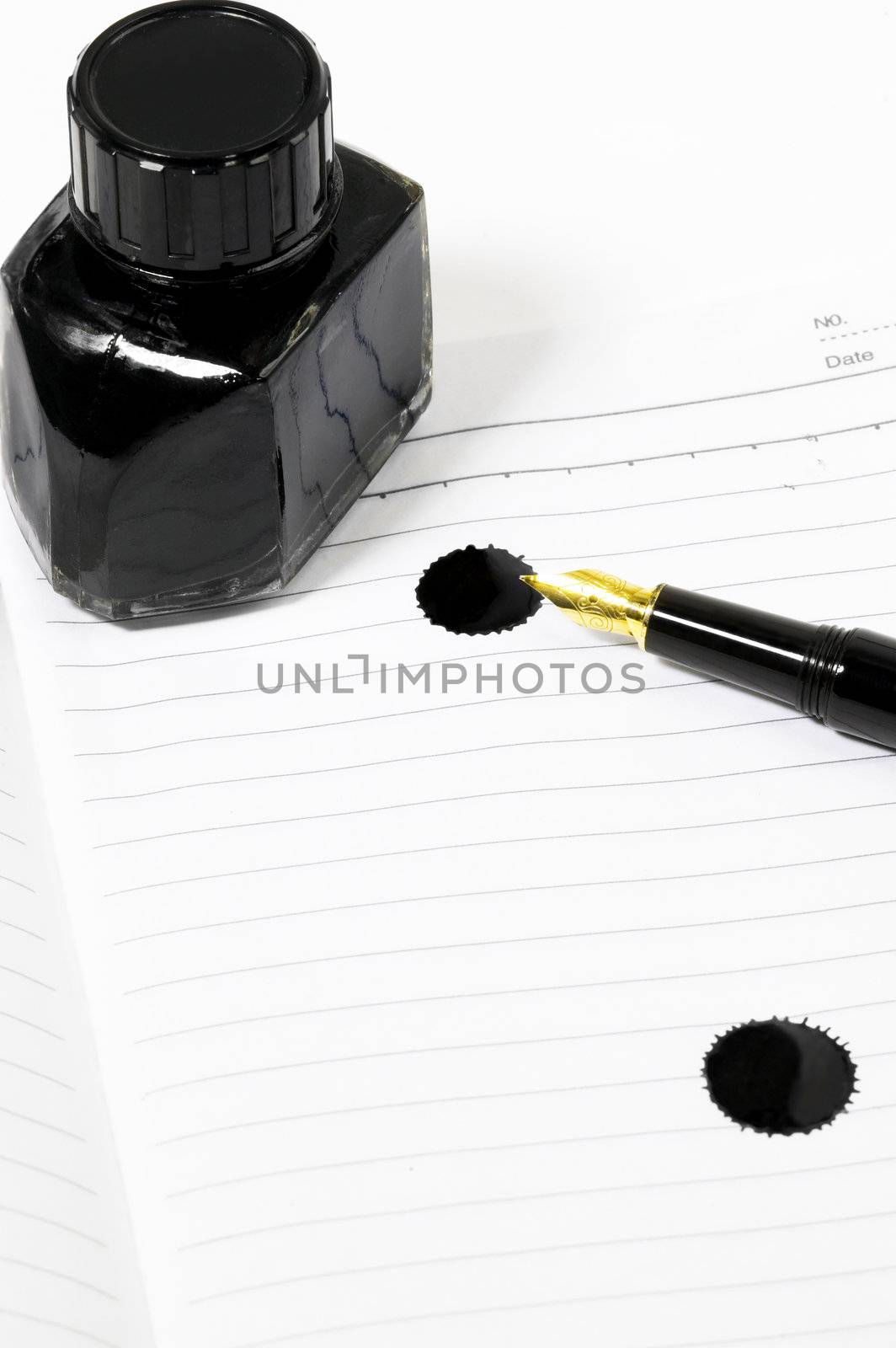 classic black fountain pen on open notebook with ink bottle with stain on page