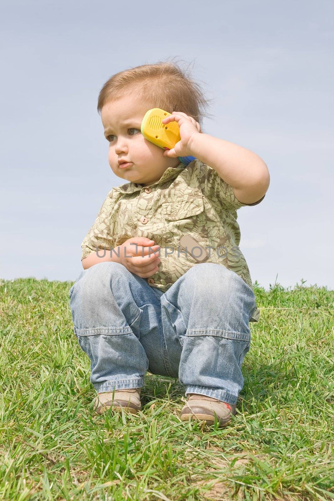Little boy holding a toy cellphone near his ear