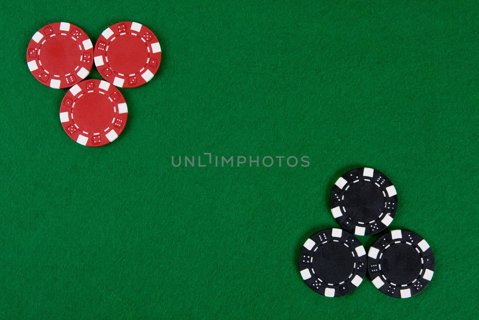 Two kinds of poker chips in two corners of a green poker table. Top view.