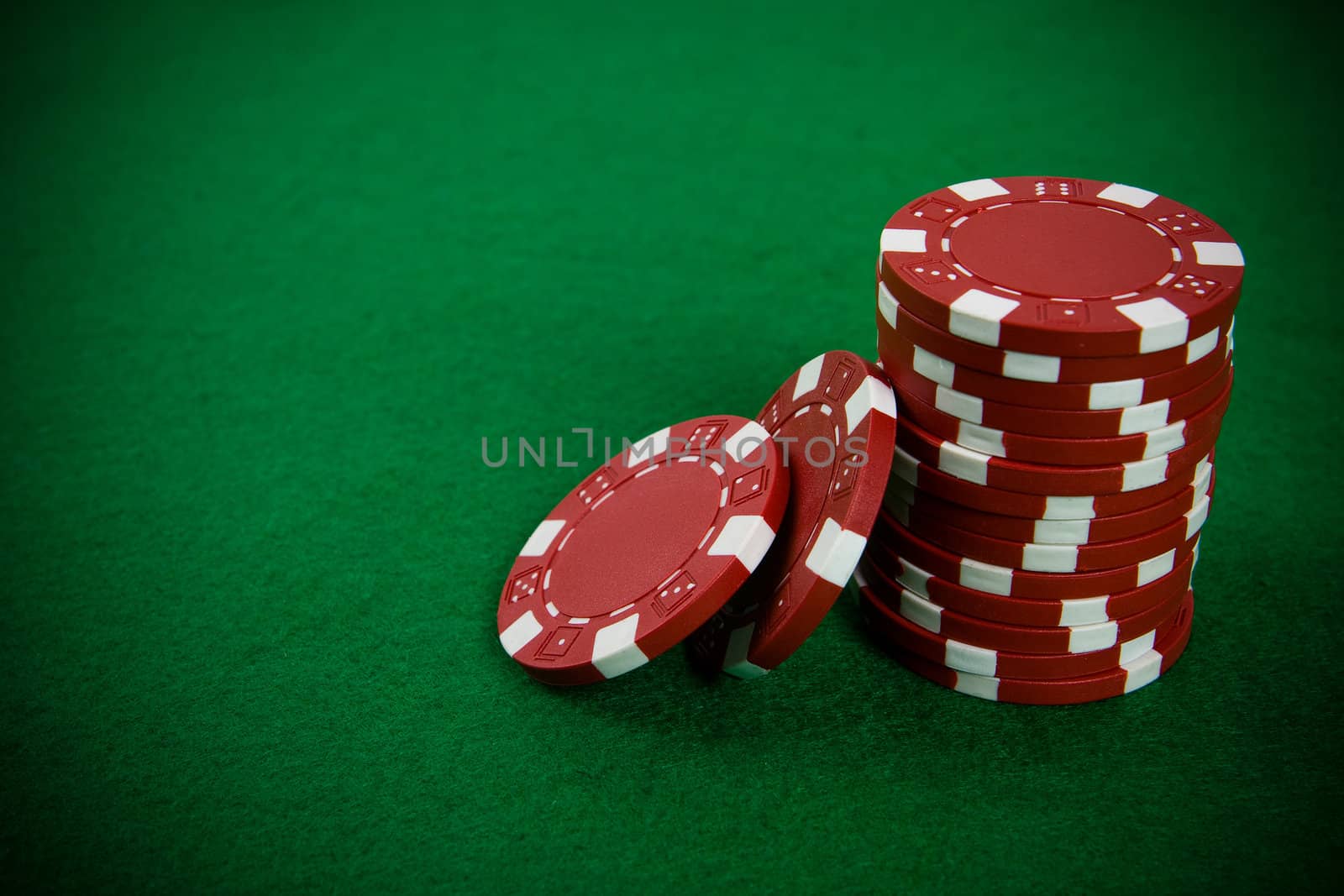 Stack of red poker chips on a green poker table background.