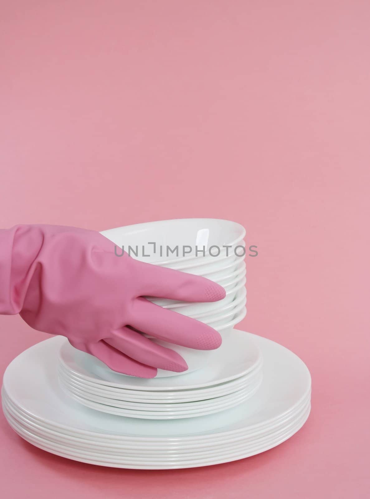 hand with pink glove holding white dishes