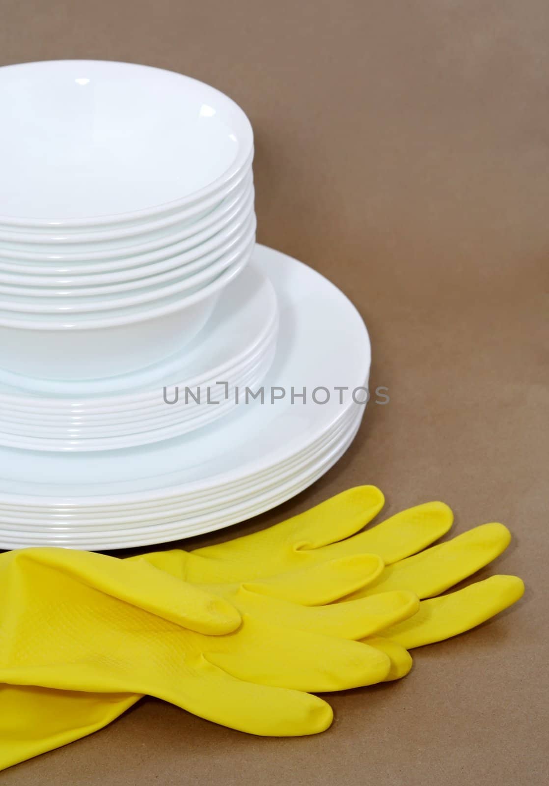 yellow gloves and white dishes stacked, brown background