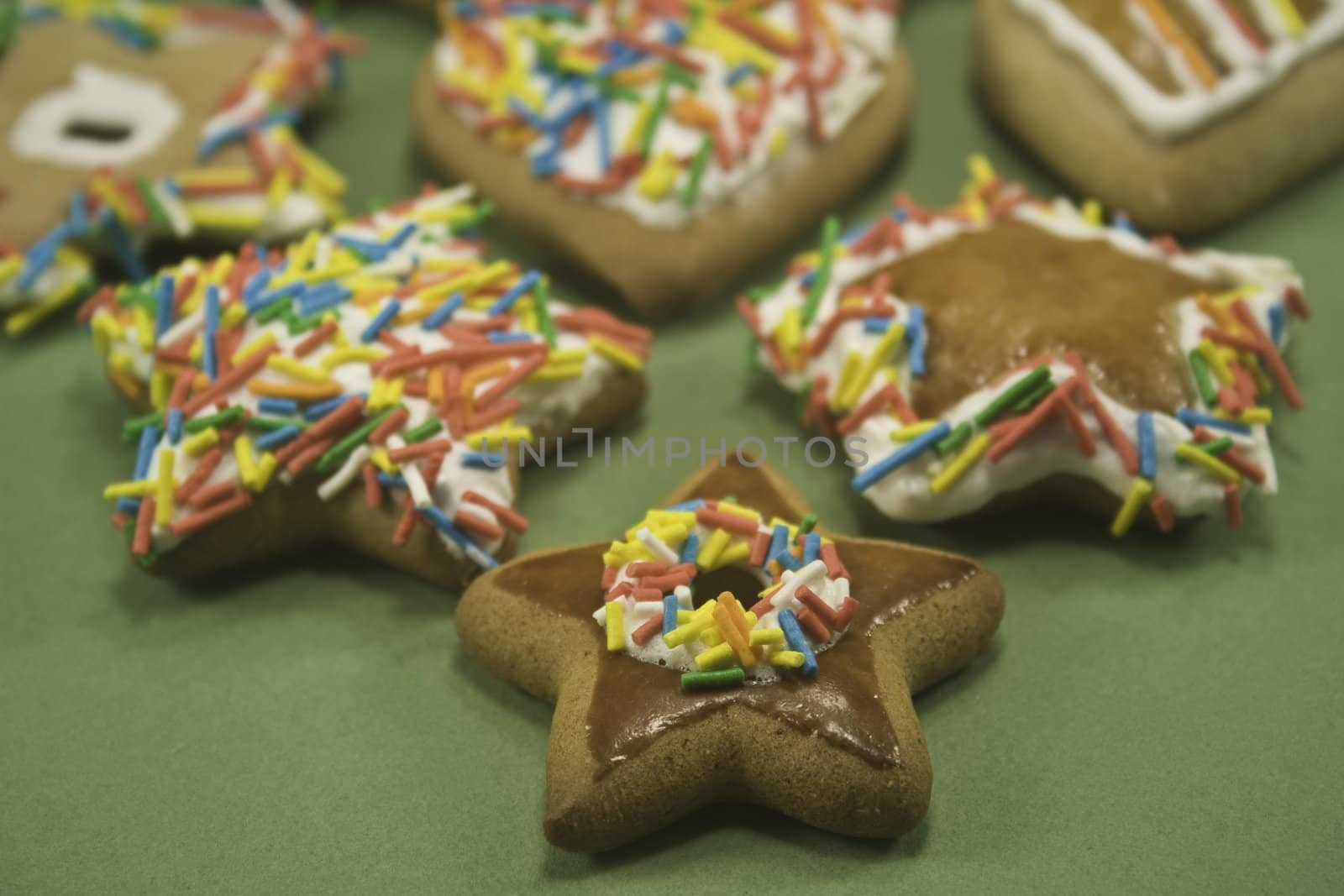 Decorated gingerbread cookies on green paper focus on front row
