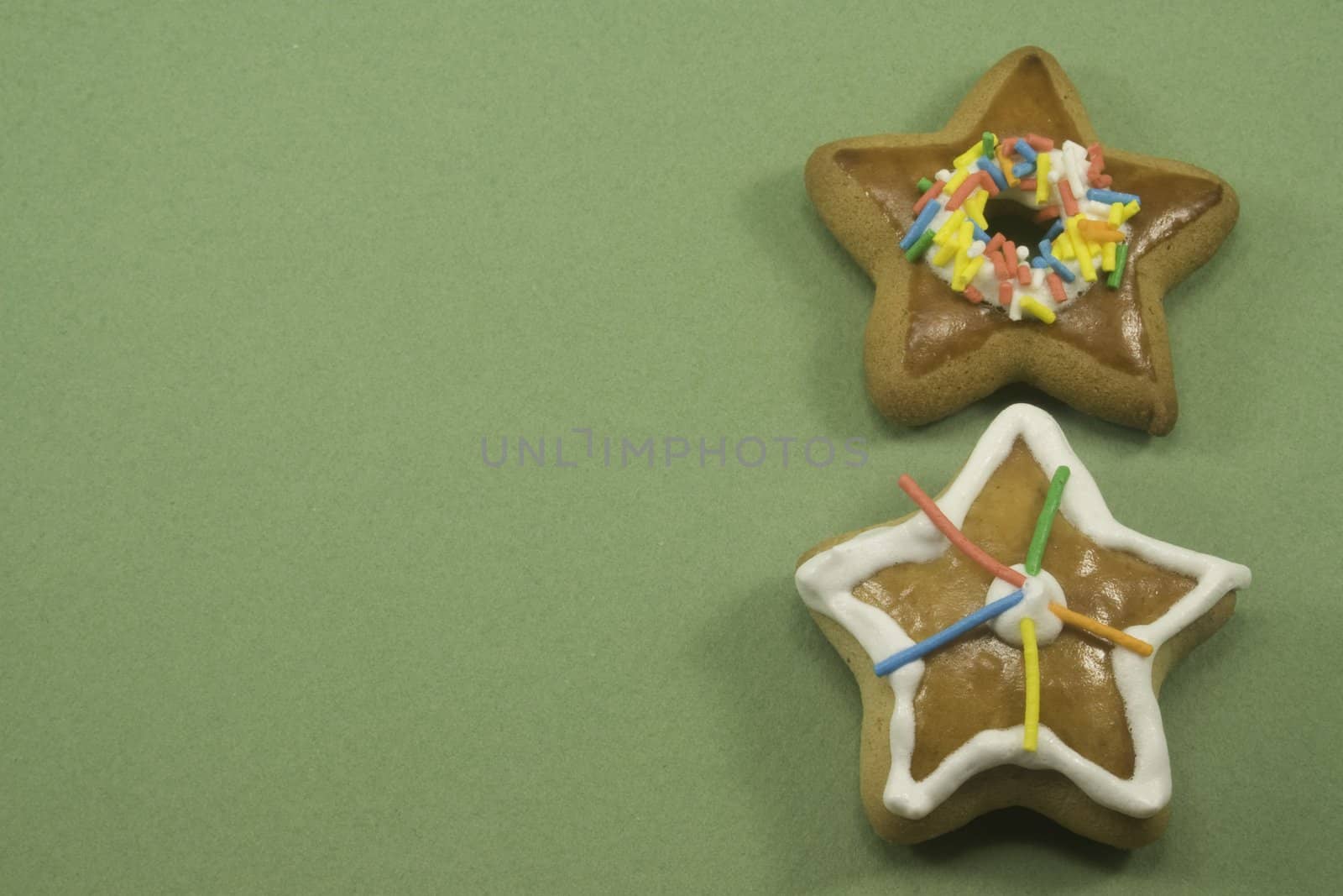 Two star Christmas cookies on green paper with copyspace on left