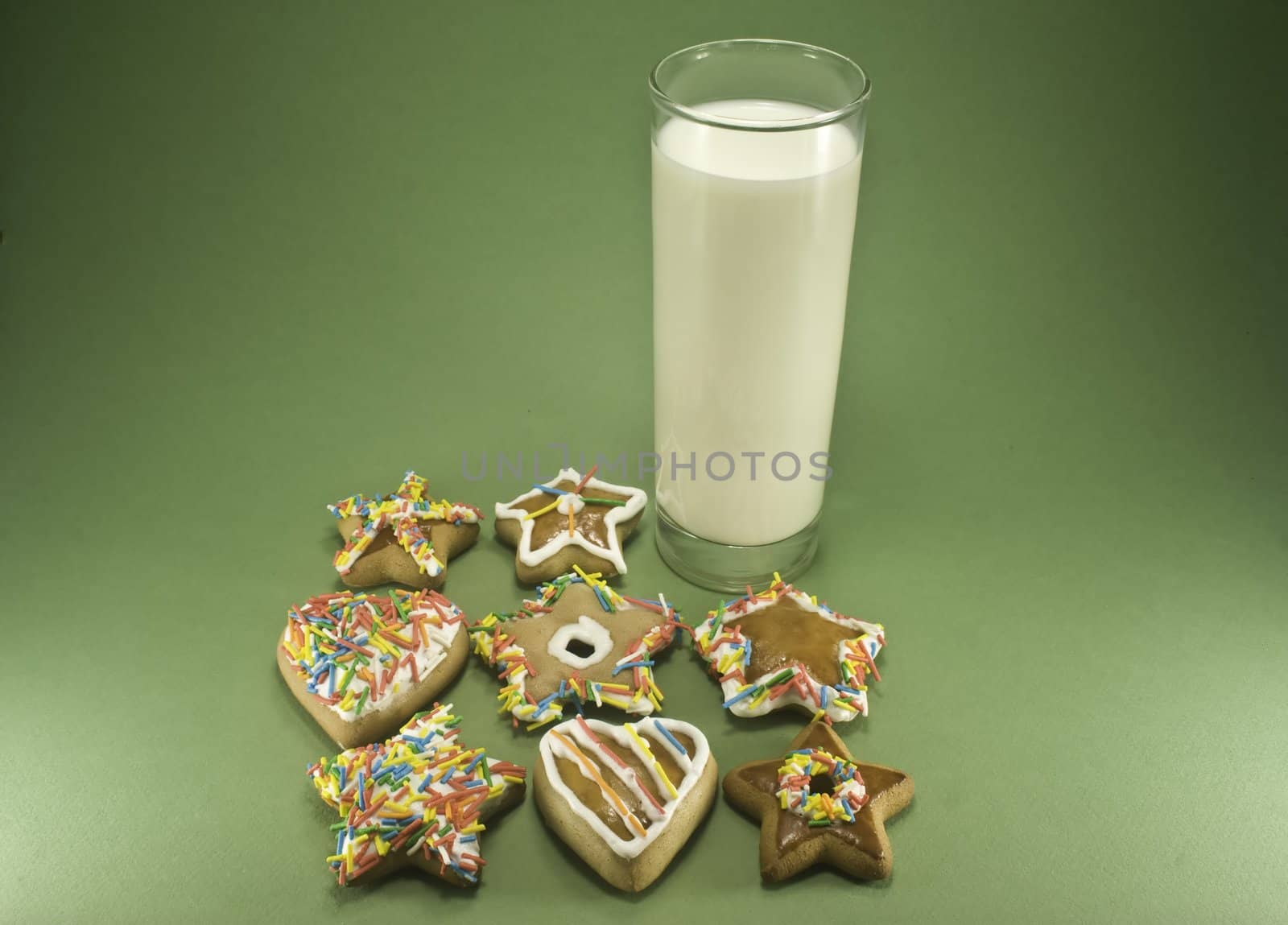 Christmas cookies and a glass of milk isolated against green paper