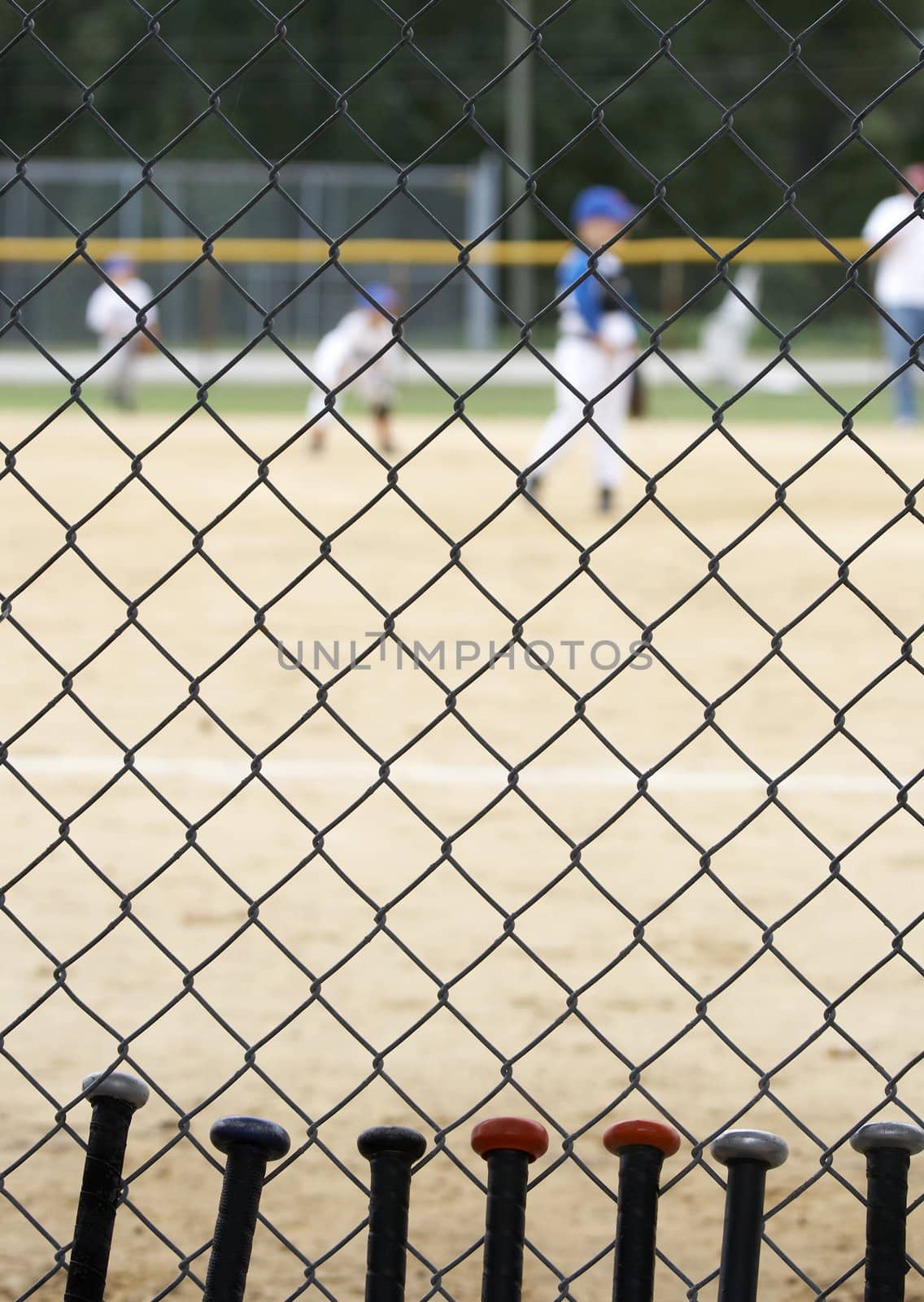 baseball bats learning against dugout fence as game is played