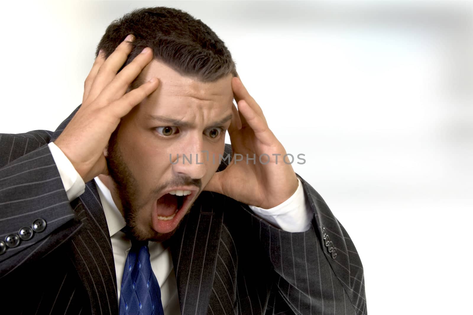 shouting businessman holding his head in his hands on an abstract  background