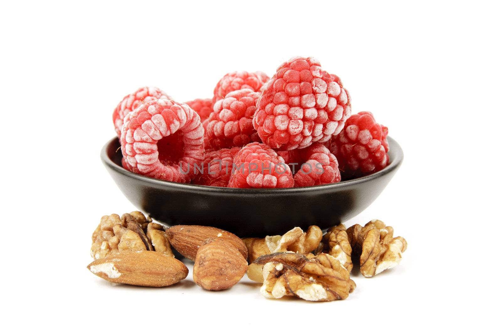 Red ripe frozen raspberries on a reflective white background