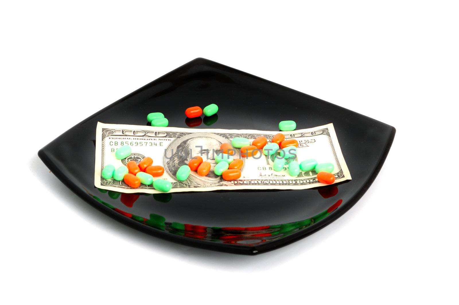 expensive chemical diet - colored pills on black asian plate and 100 dollar banknote