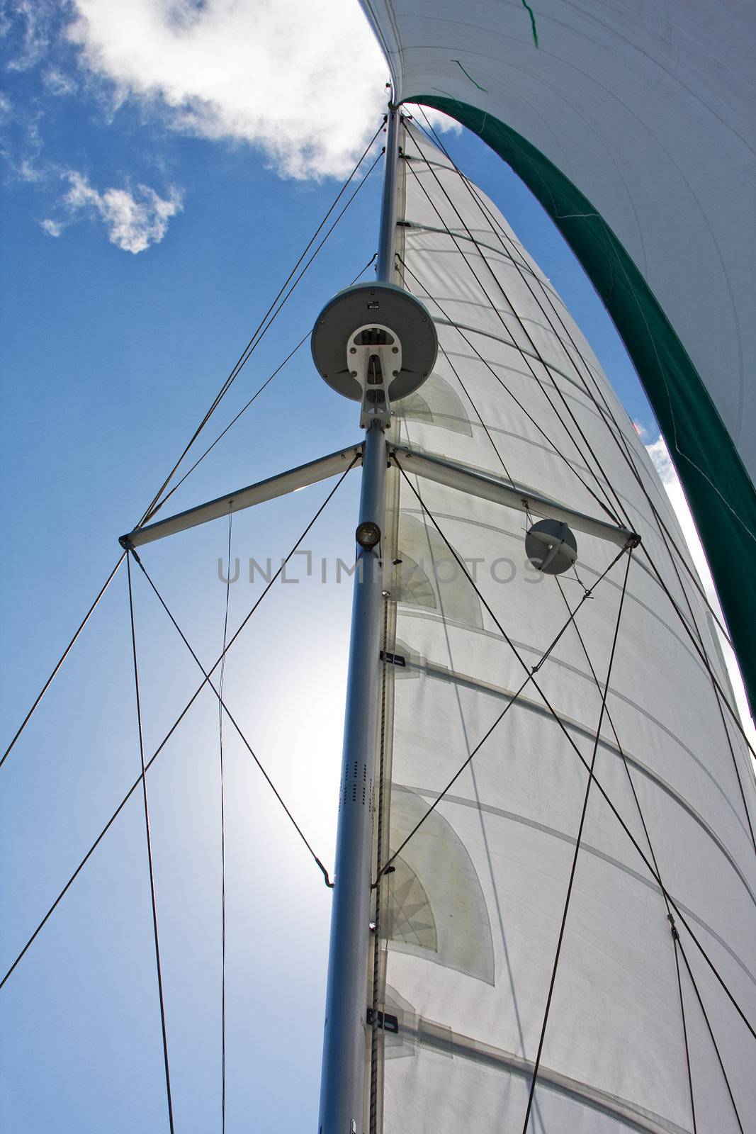 Mast and sails with radar and GPS standing tall with deep blue sky and white cloud