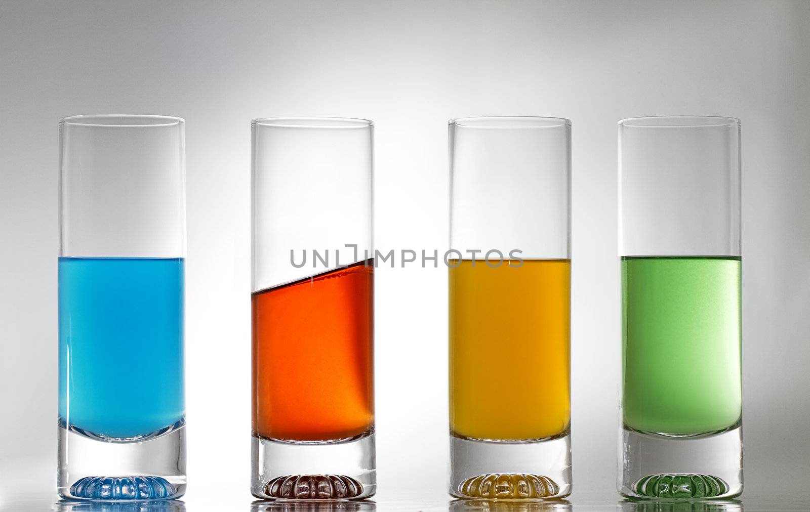 four glasses with some coloured liquid and one is different