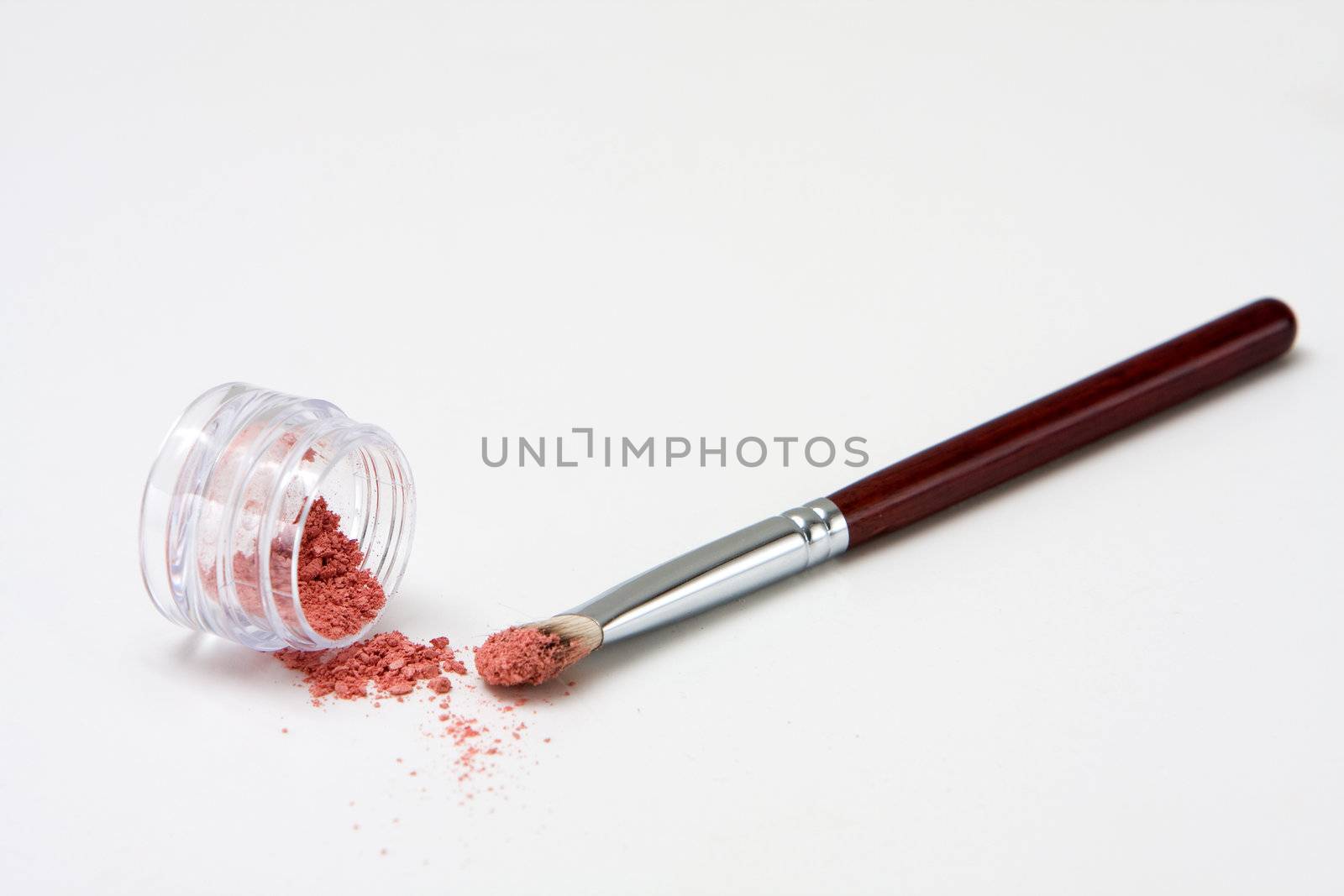 Translucent pink powder in a jar and on brush, isolated