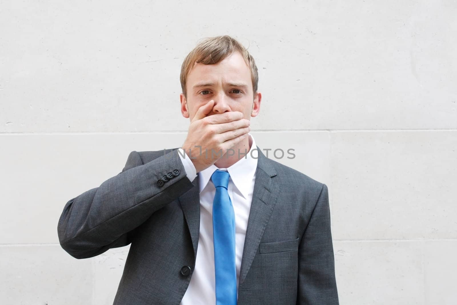 A business man being silent, holding a hand over his mouth