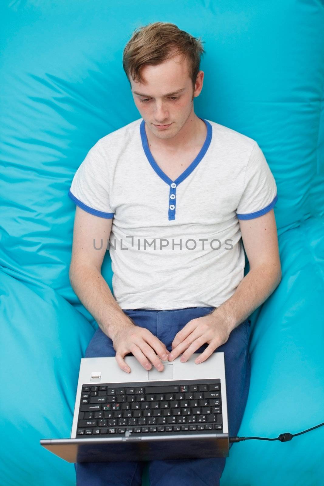 A teenager with a laptop computer on his lap