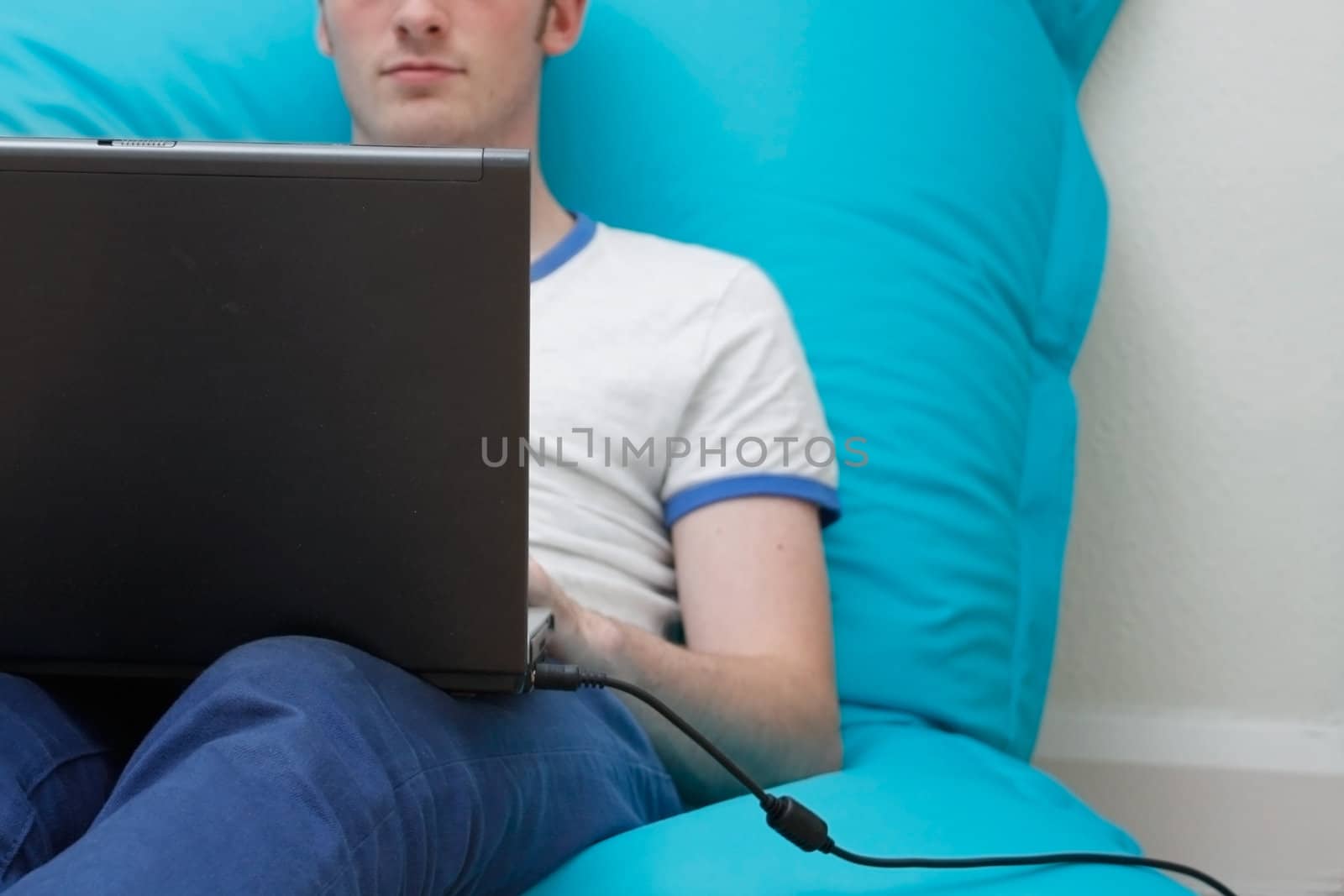 A teenager with a laptop computer on his lap