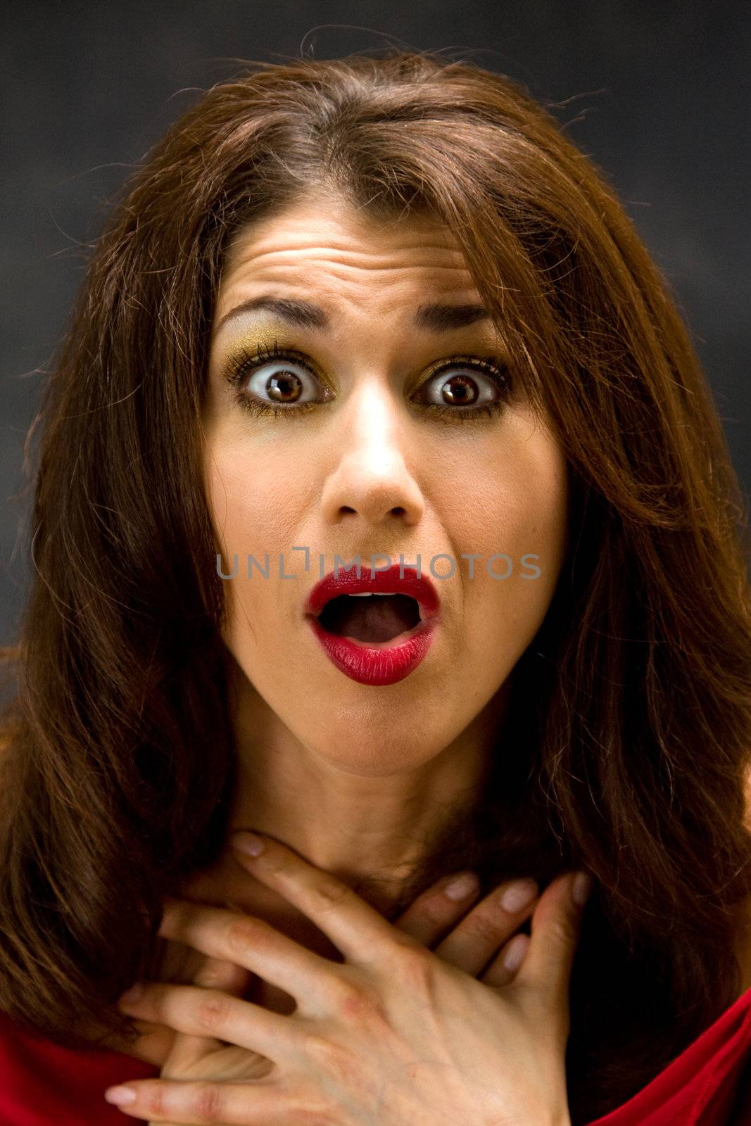 Beautiful woman with shocked expression dressed and mouth open and hands on chest