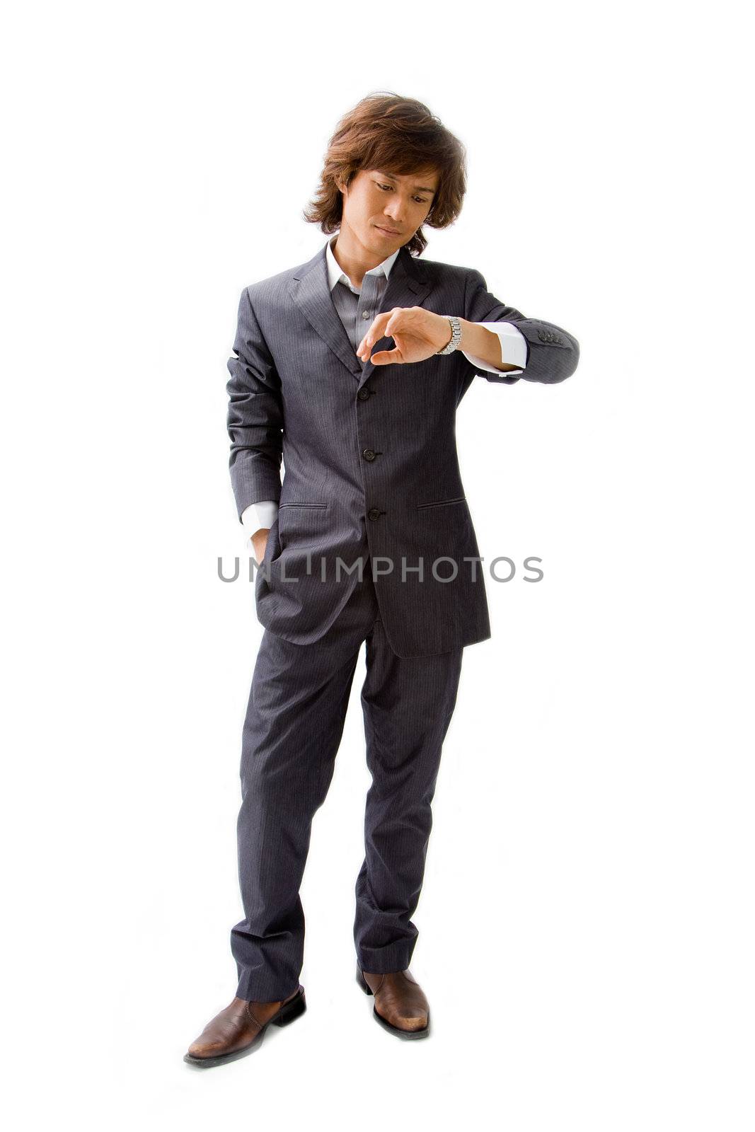 Young Asian business man dressed in a gray pinstripe suit with hand in pocket and looking at his watch, isolated