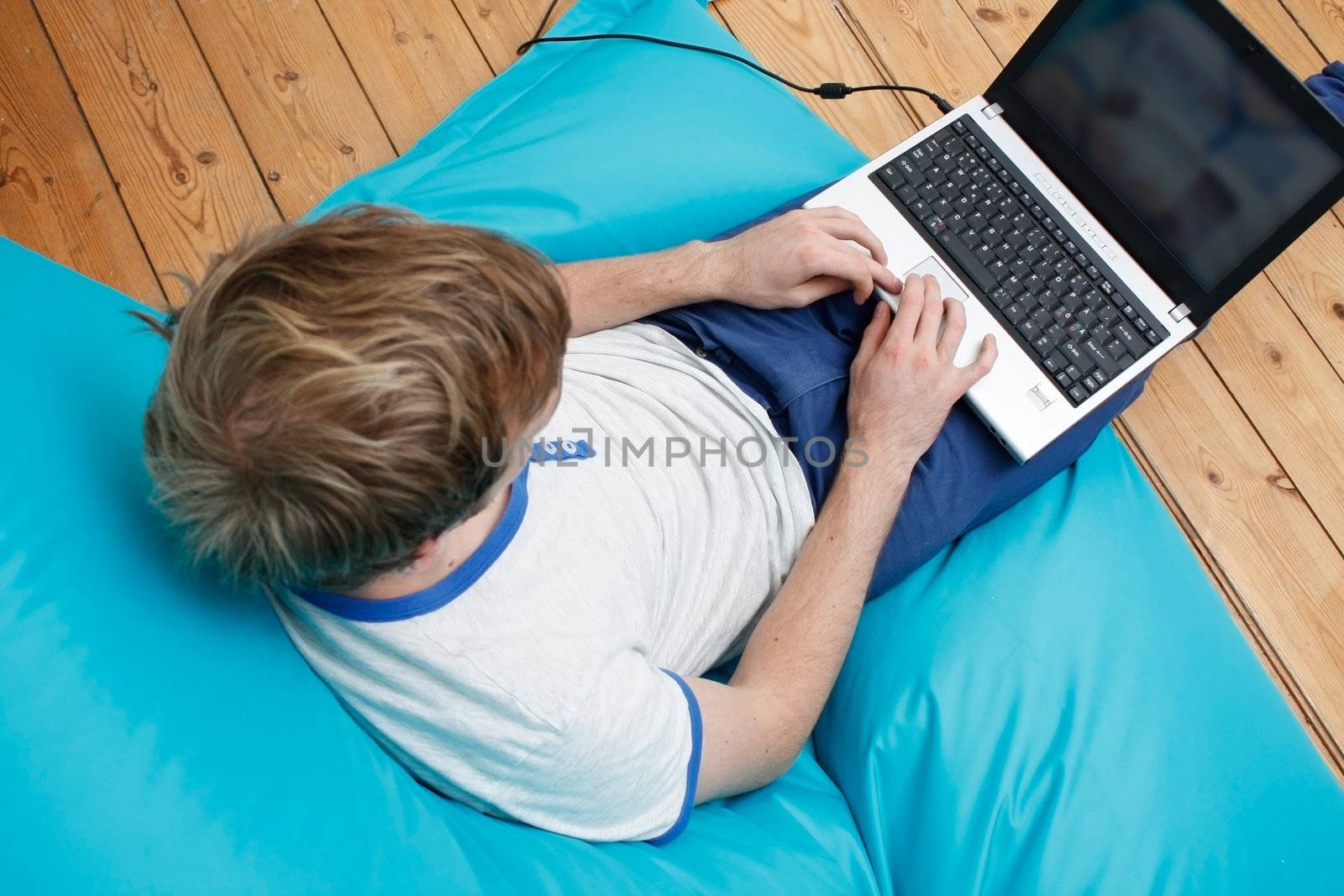 A teenager with a laptop computer on his lap