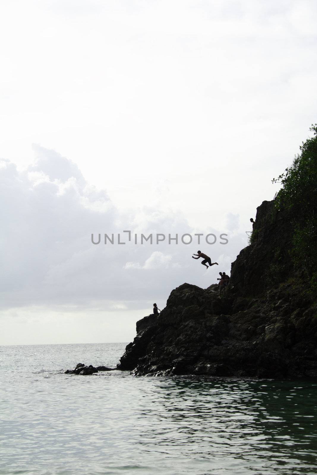 Jumping off a rock into the ocean, silhouette.