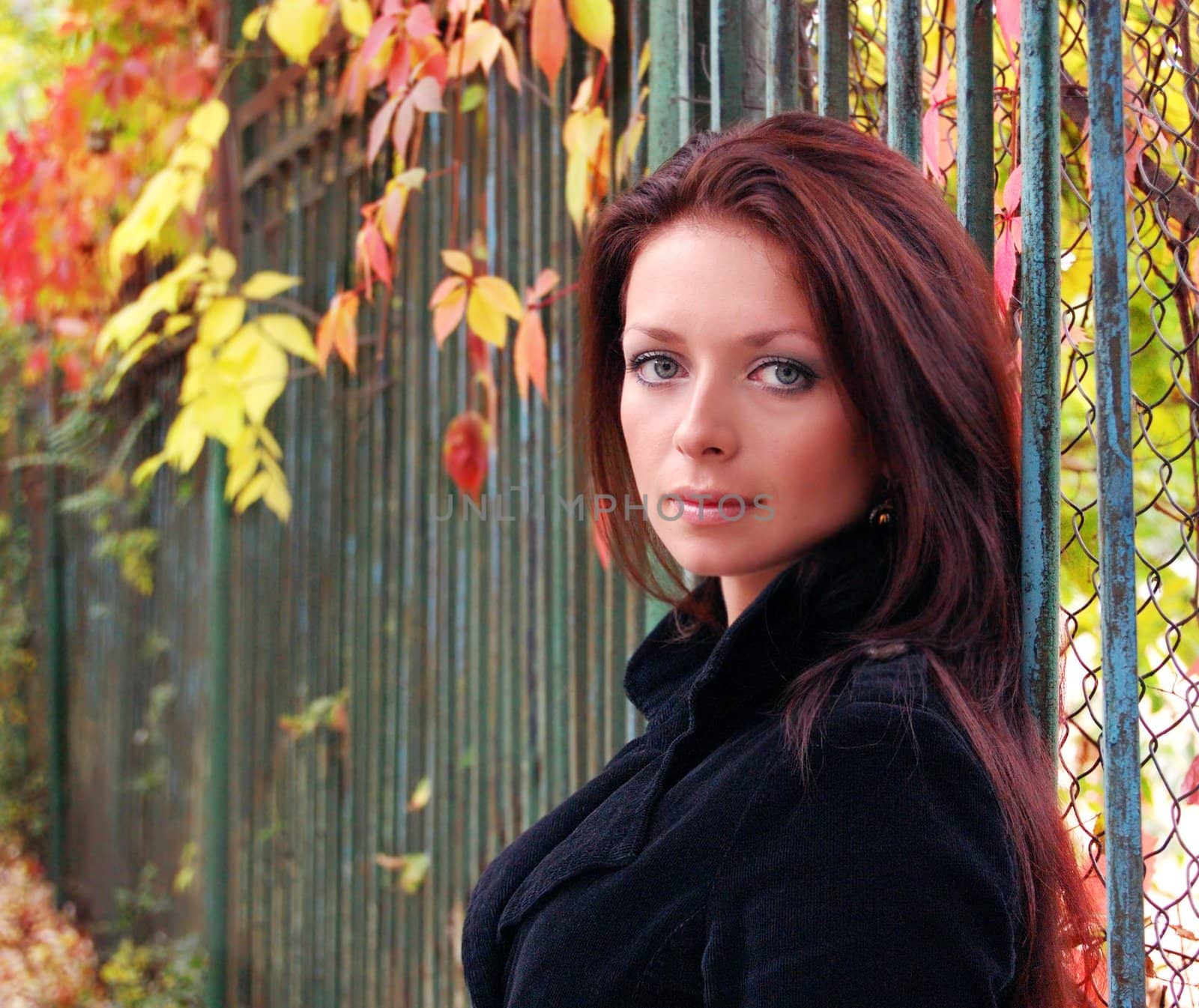 Beautiful autumn portrait of brunette woman standing near fence