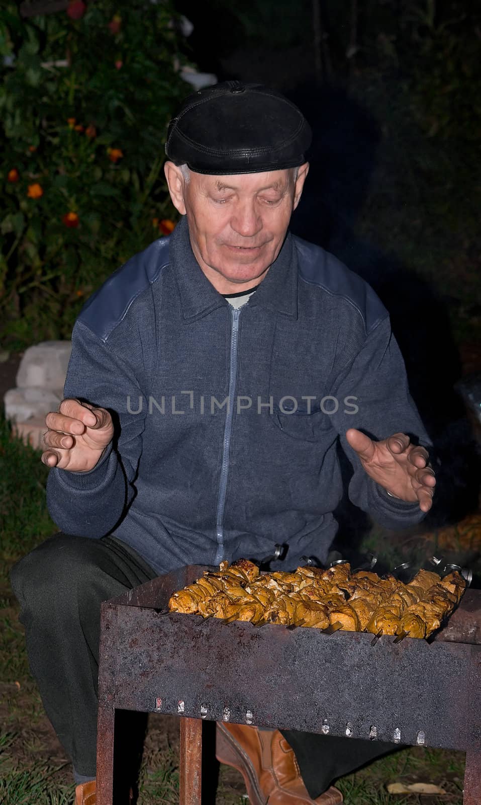 The elderly man prepares a shish kebab on picnic