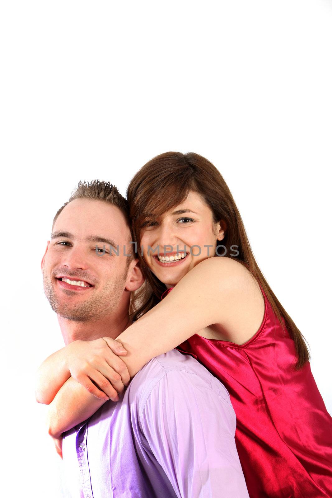 A young couple in love. The young man takes the young woman on his back. Both laugh in camera direction.