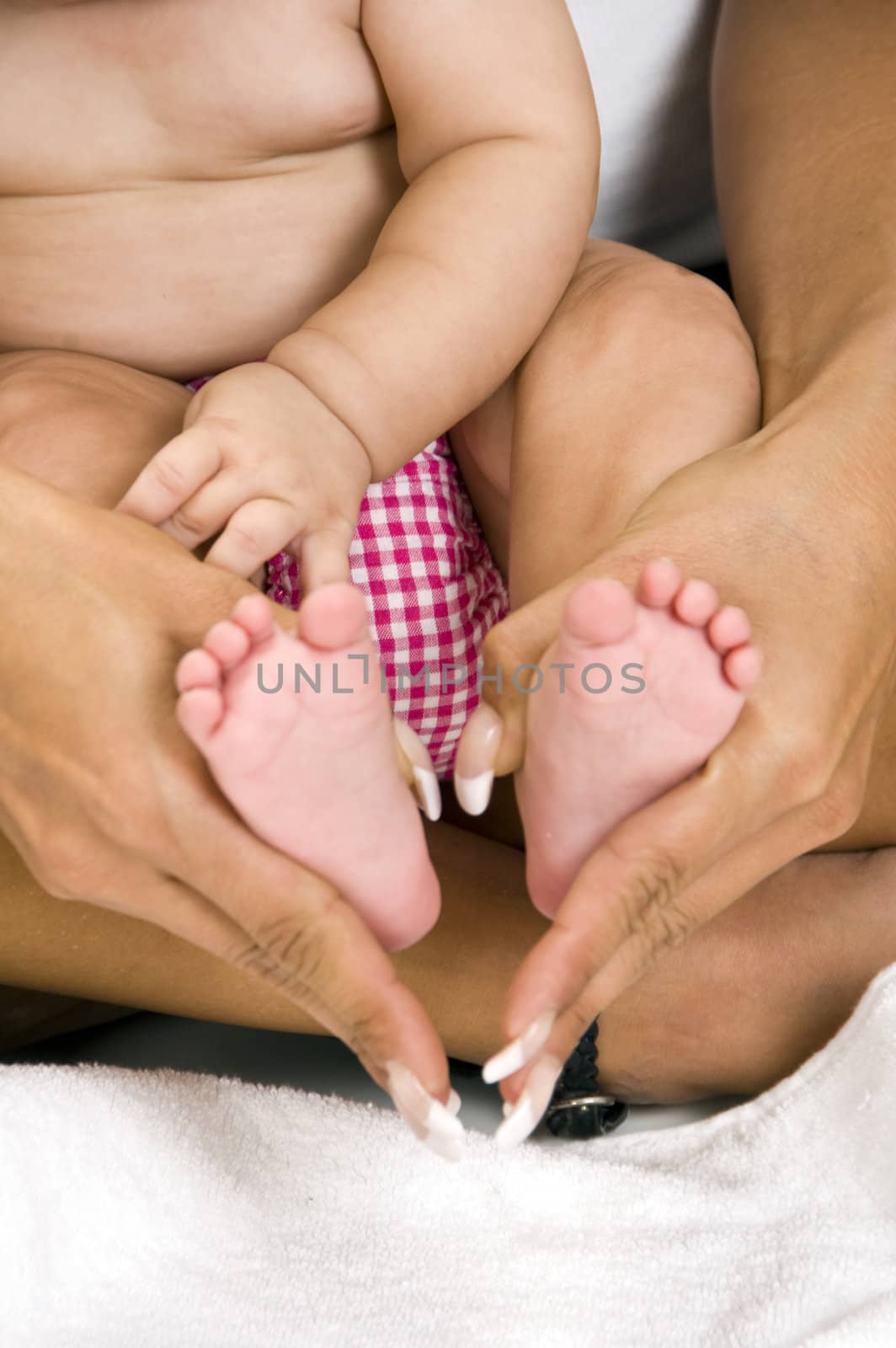 mother holding her child's feet on an isolated white background