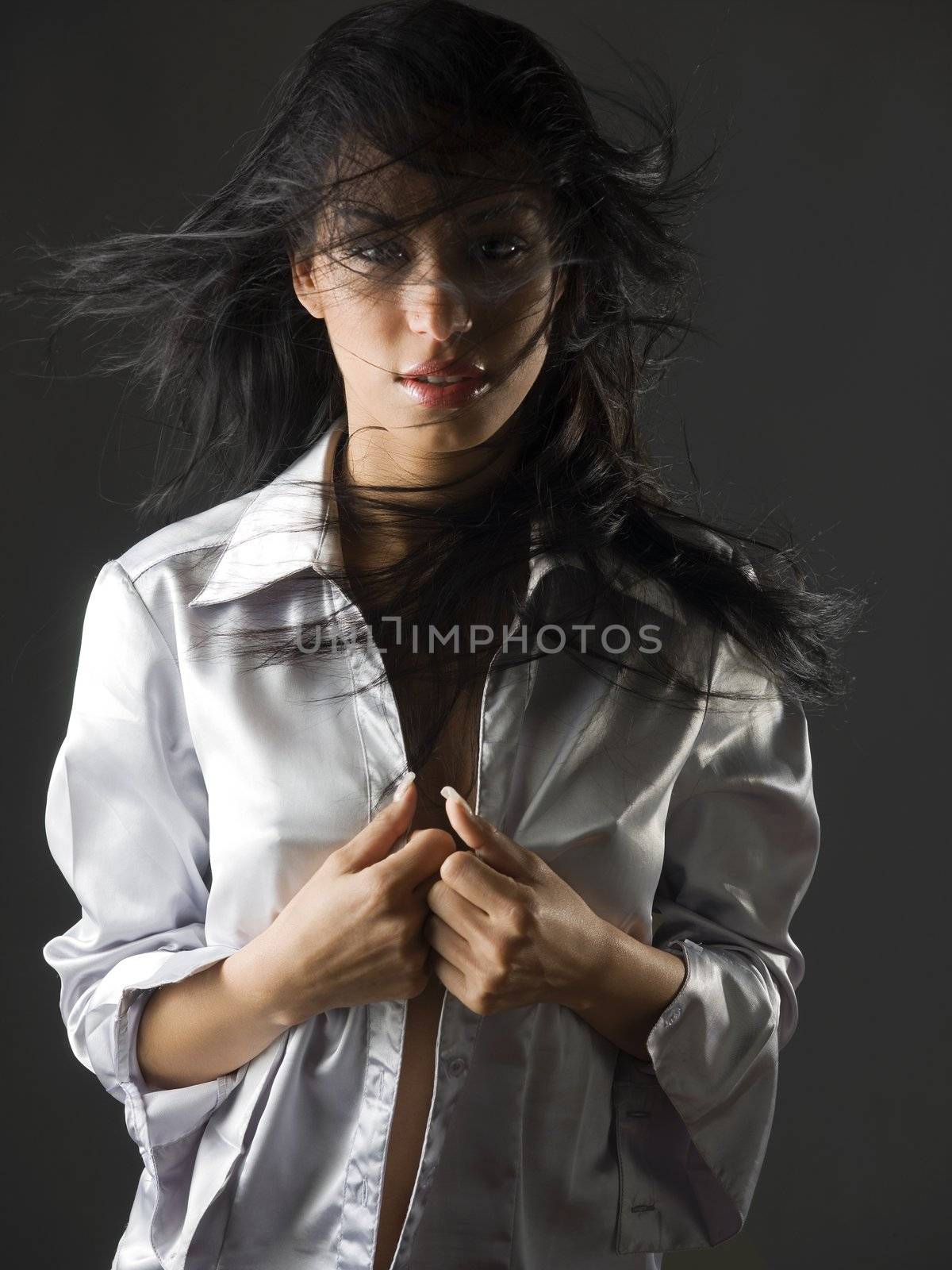 beautiful portrait of a young and very cute latina girl with a fatal look and the hair flying on her face