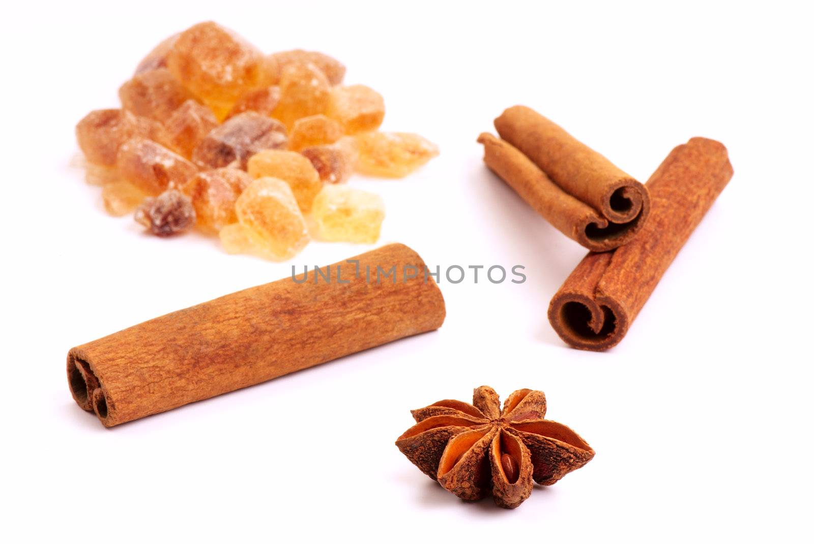 Star anise, three cinnamon sticks and brown sugar on a white background