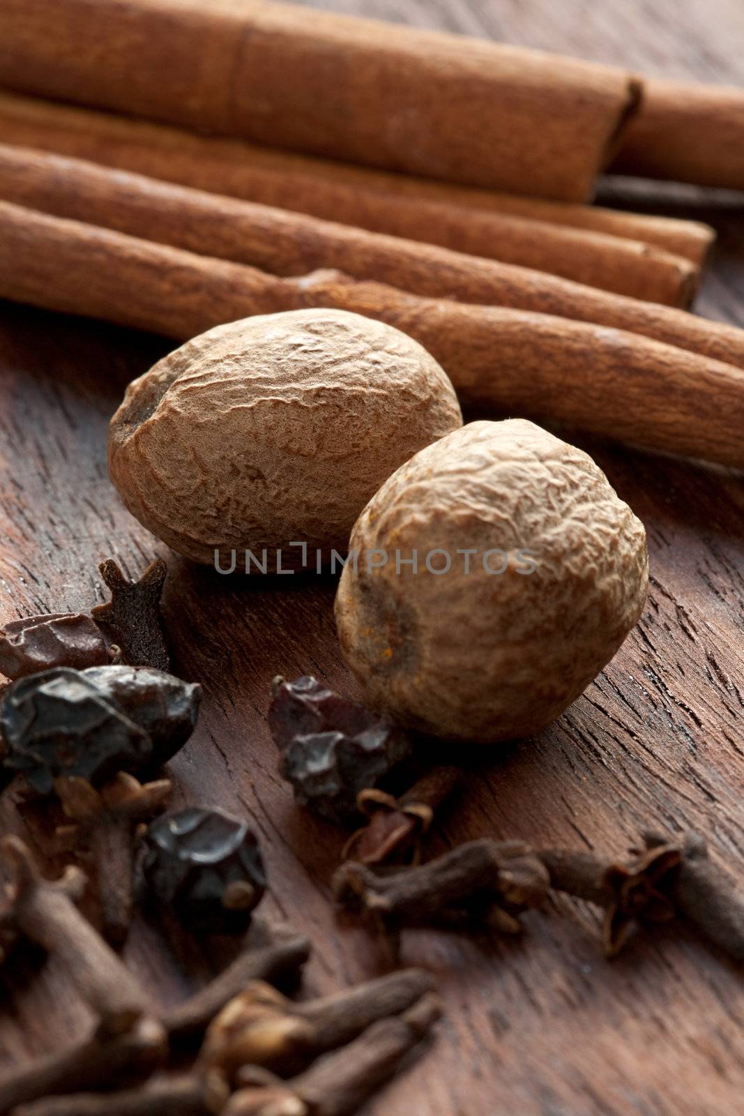 Cinnamon, nutmeg, cloves and other spices on wooden background