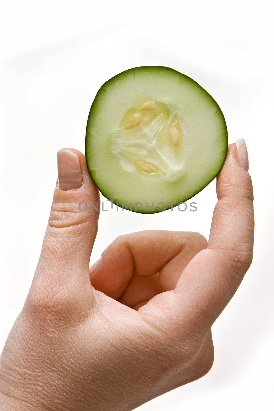 Woman hand holding up a wedge of cucumber, isolated on white