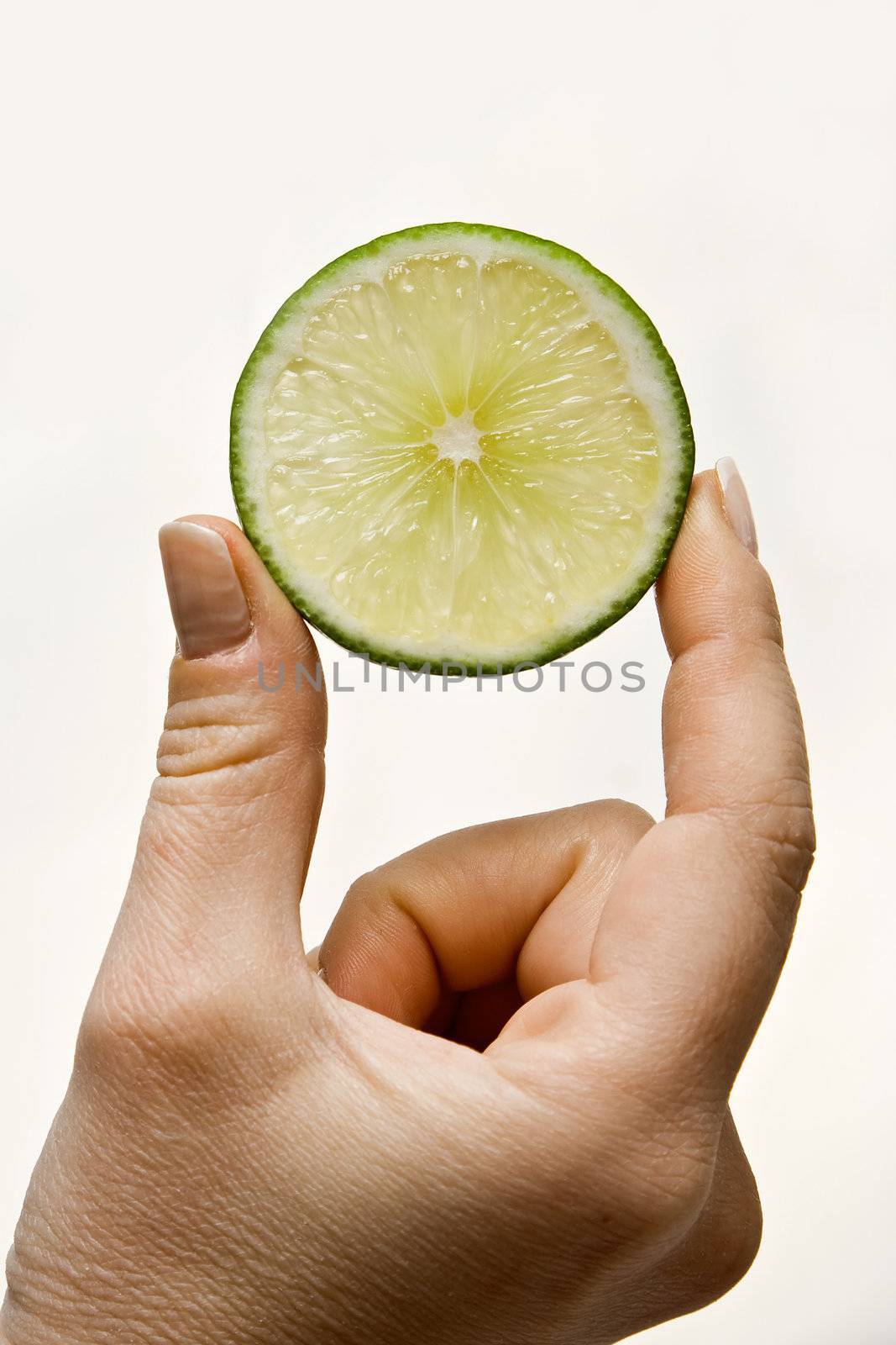 Woman hand holding up a wedge of lime, isolated on white