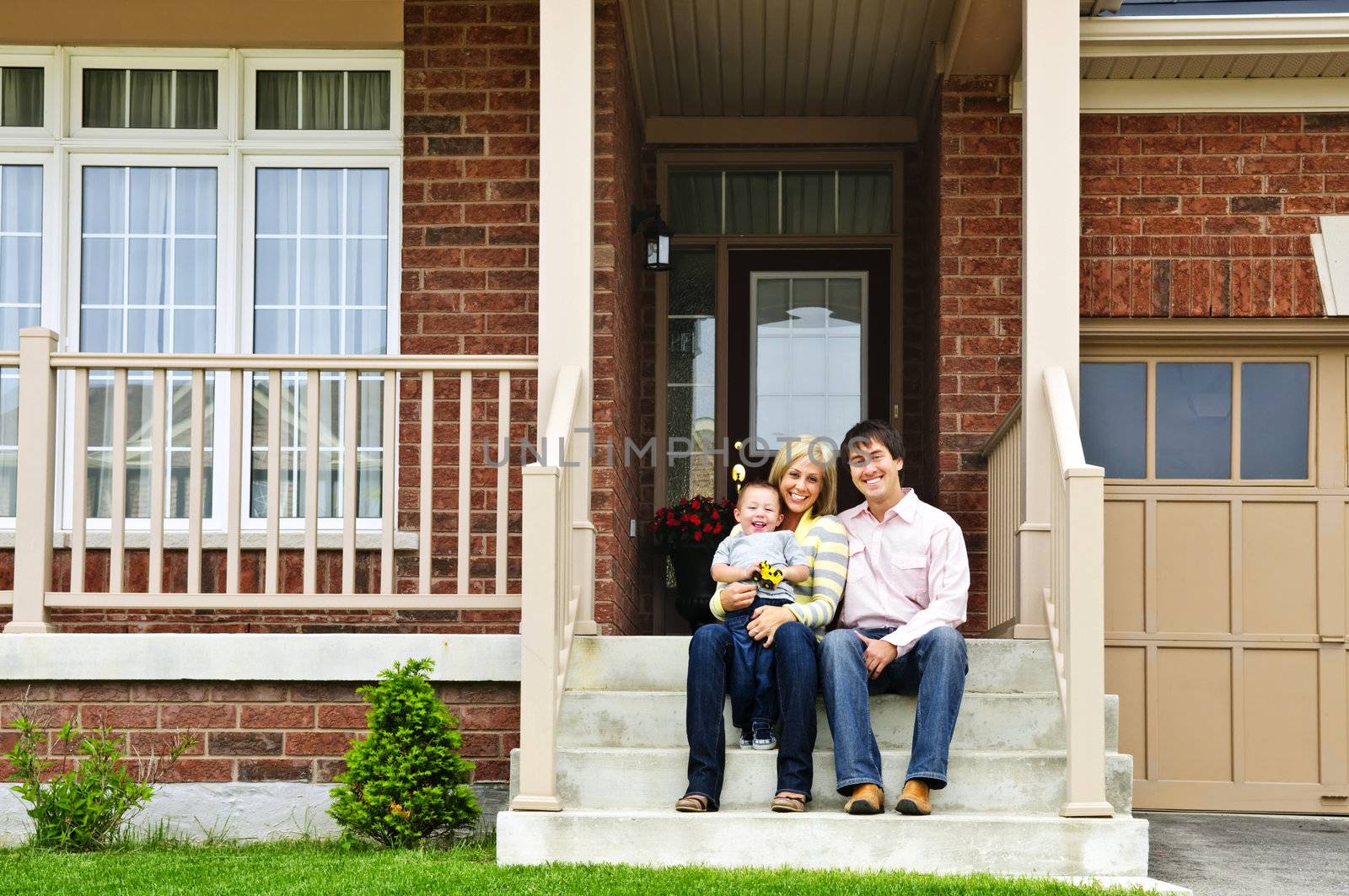 Young family sitting on front steps of house