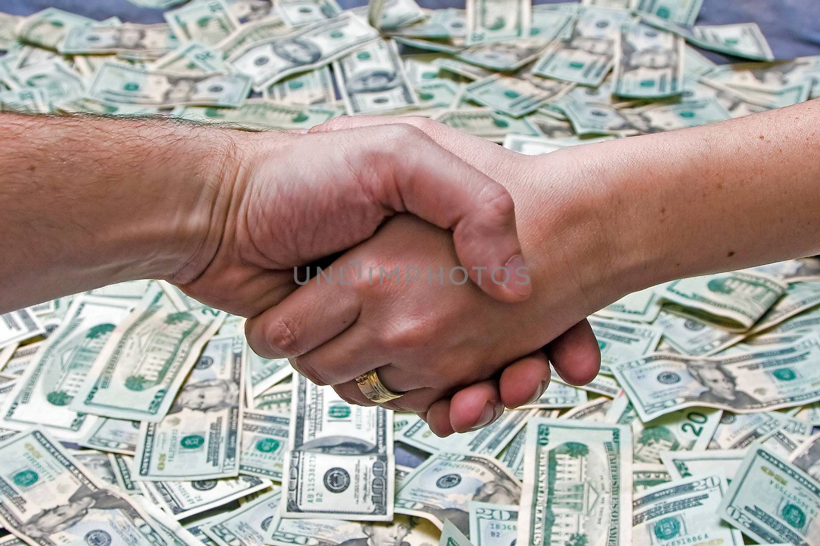 Two shaking hands above a layer of lots of money