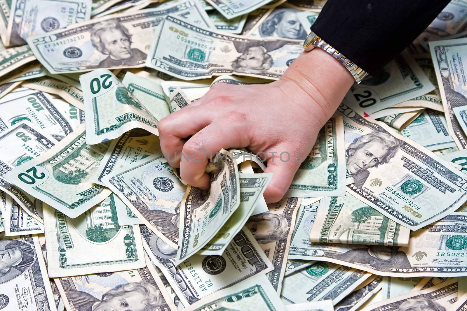 Womans hand grabbing money from a huge pile of dollars