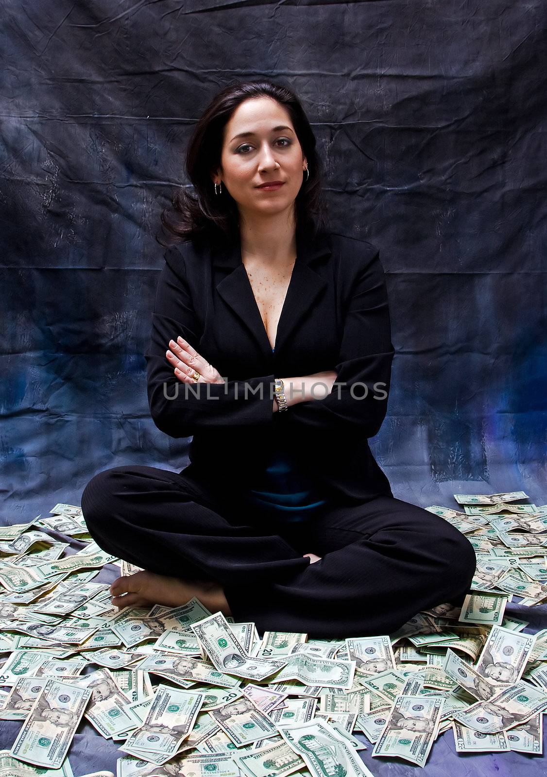 Rich woman sitting with crossed arms in money isolated on a dark background