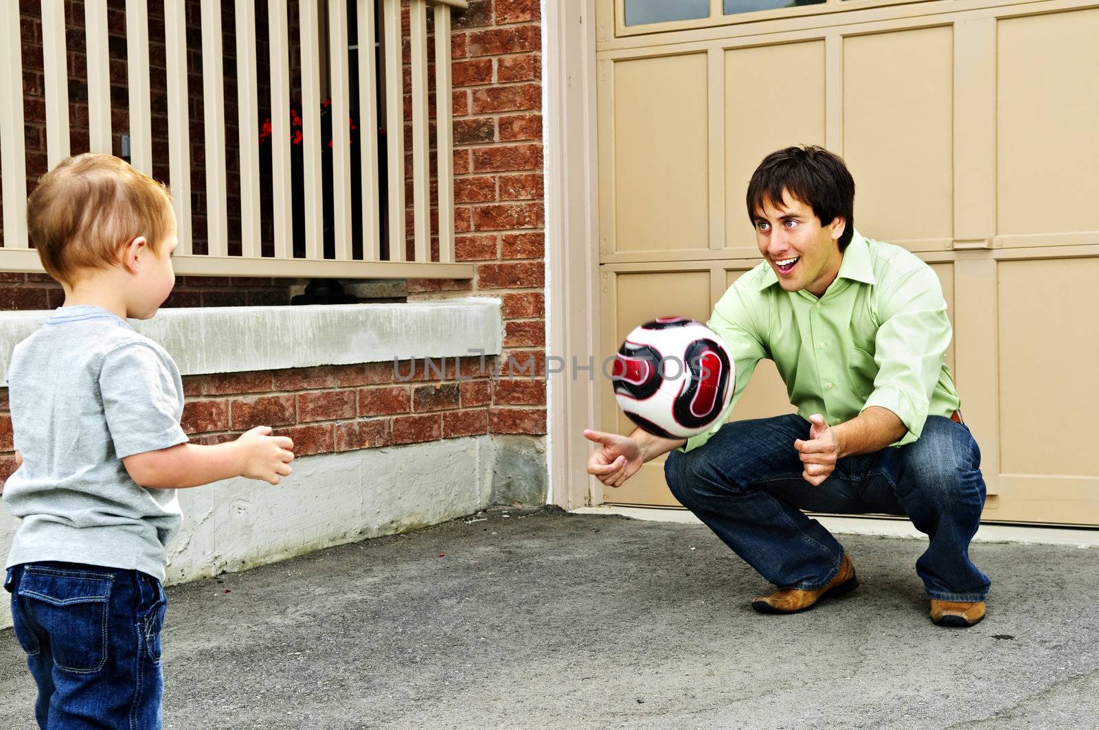Father teaching son to play soccer on driveway