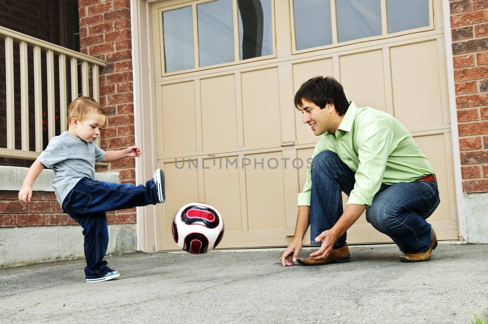 Father and son playing soccer by elenathewise