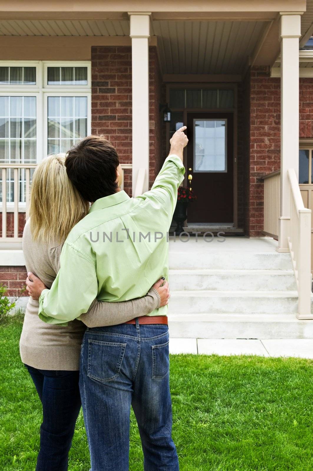 Happy couple in front of home by elenathewise