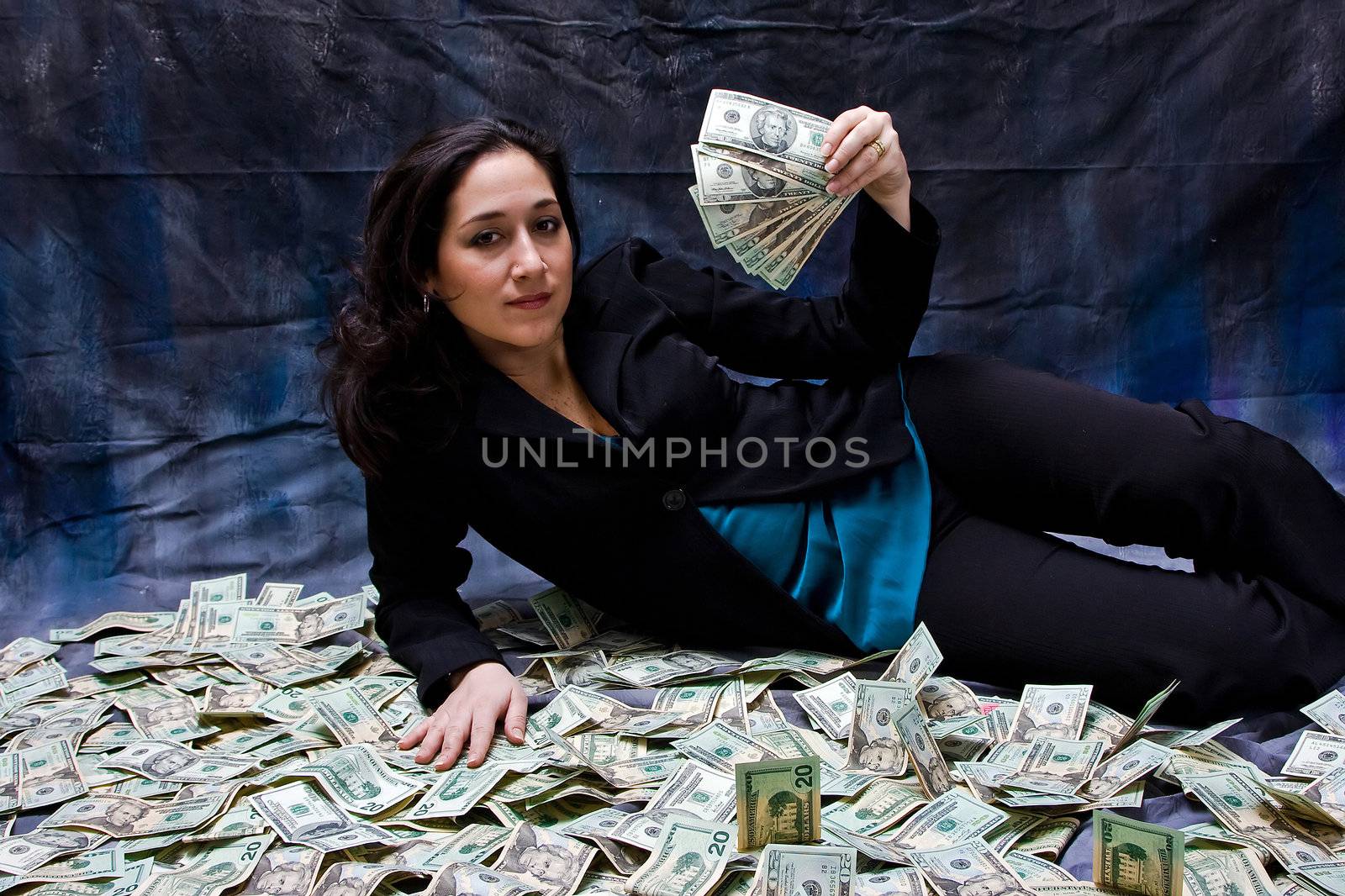 Rich business woman waving money and laying with her money isolated on a dark background