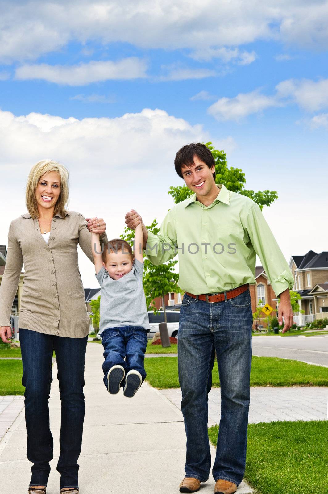 Young happy family playing with son on sidewalk