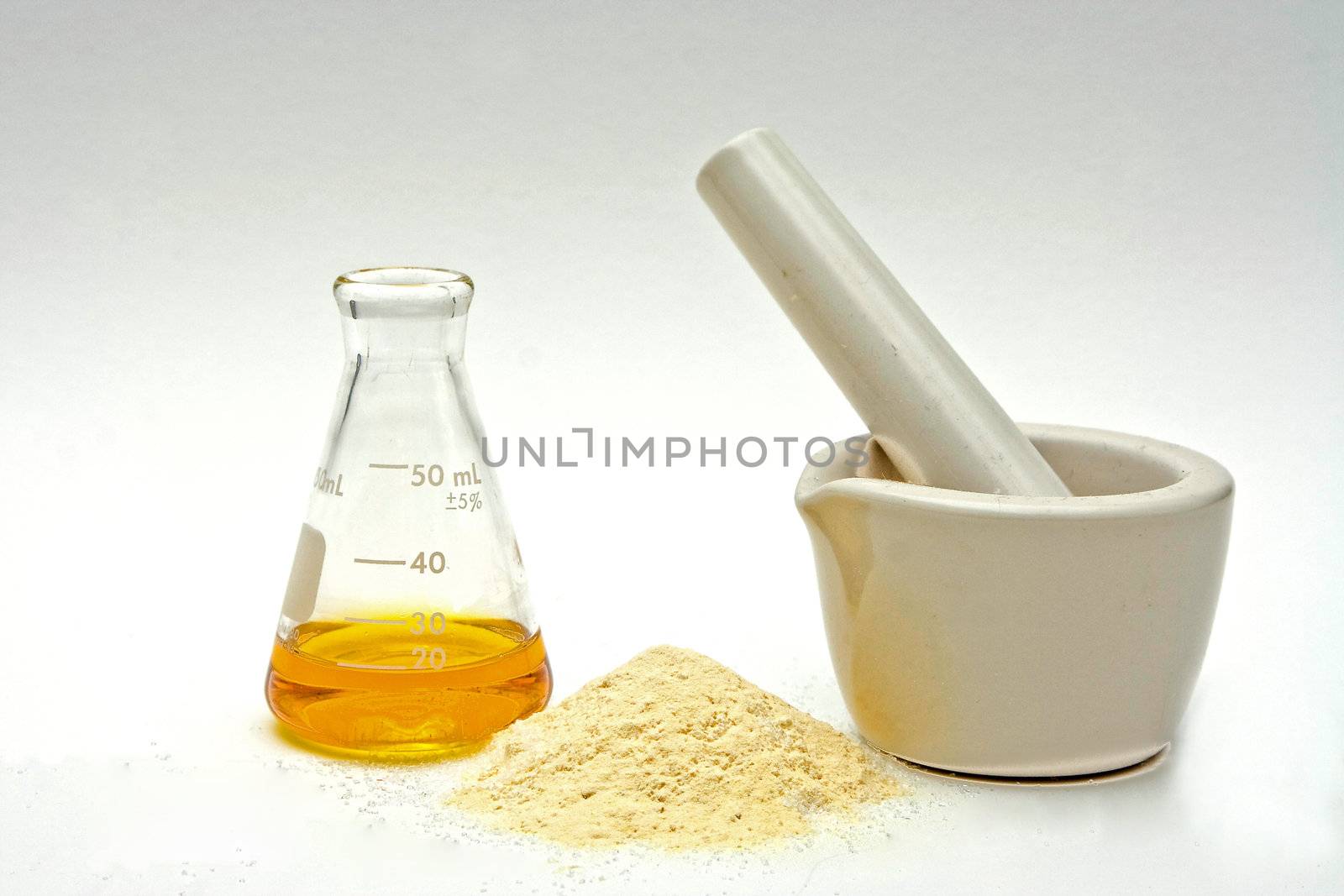 A yellow liquid in a flask with a powder in front and a white mortar on a white background