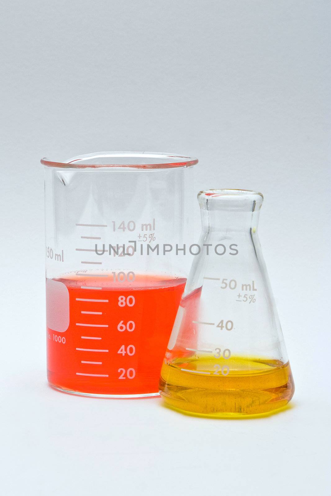 Flask and beaker with colorful liquids as pH indicators on a white background