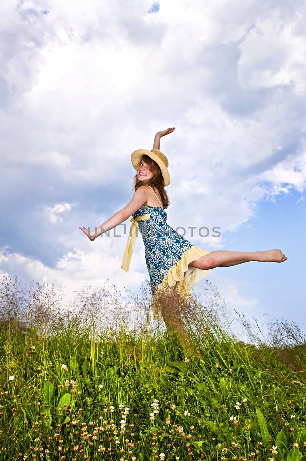 Young teenage girl dancing in summer meadow amid wildflowers