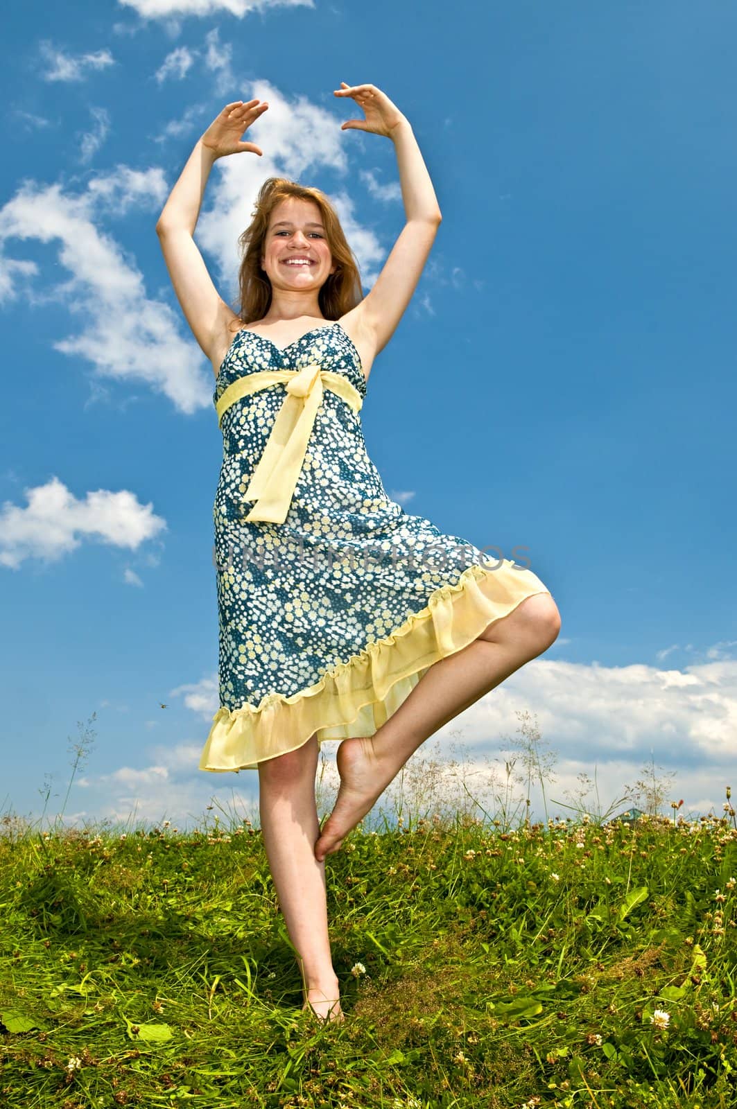 Young teenage girl dancing in summer meadow amid wildflowers