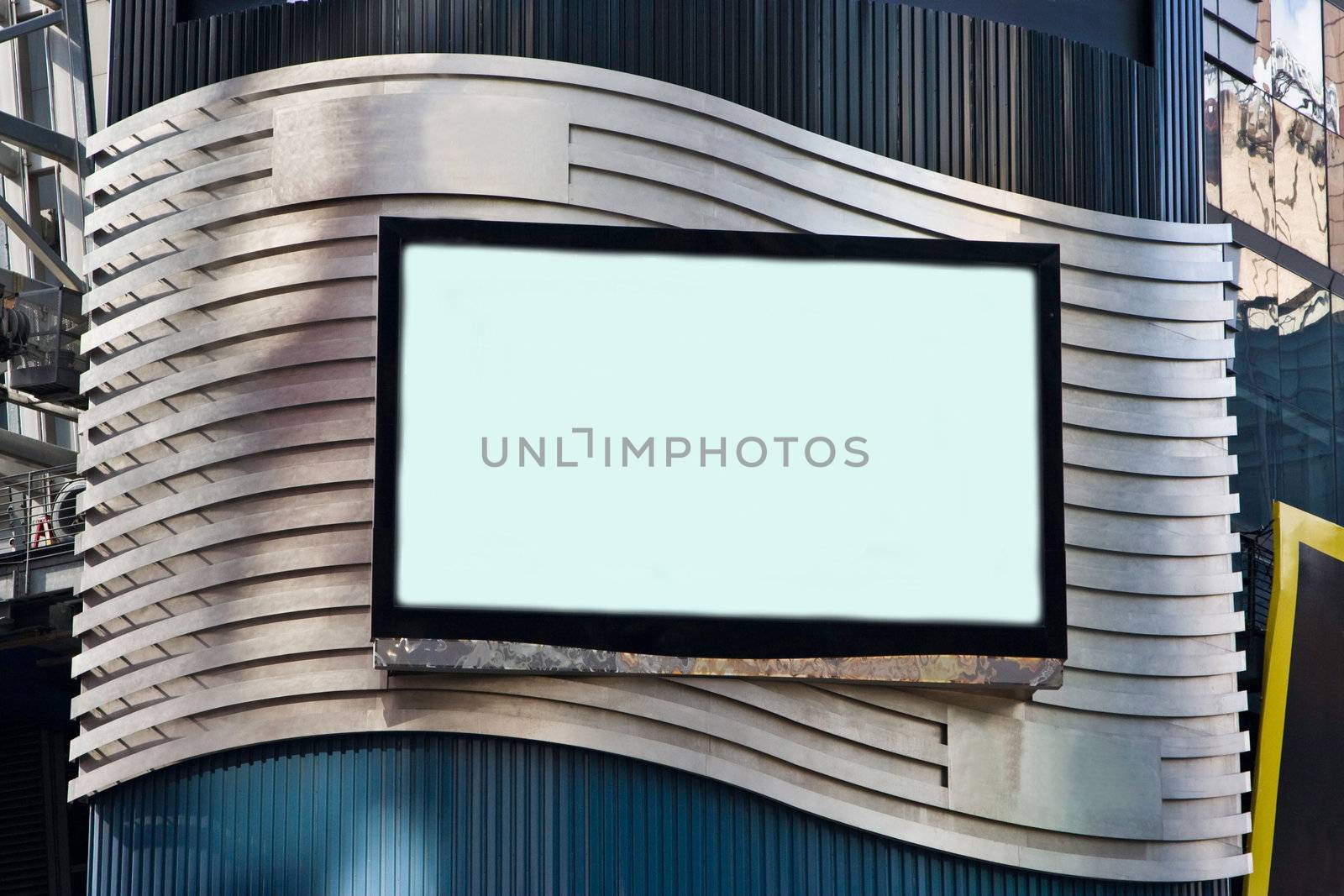 A LCD TV on a building for advertisement; used as a billboard; frame with black border; on a silver colored waved background.