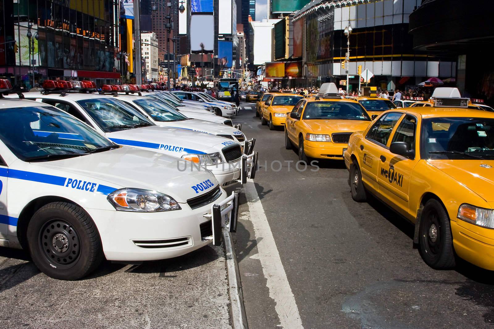A typical vision on the streets if New York City; A line up of Police cars and Taxi Cabs driving on Broadway through Times Square.