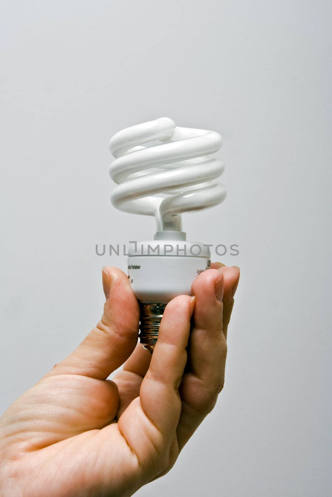 A female hand presenting a environmental friendly and power saving fluorescent light bulb.