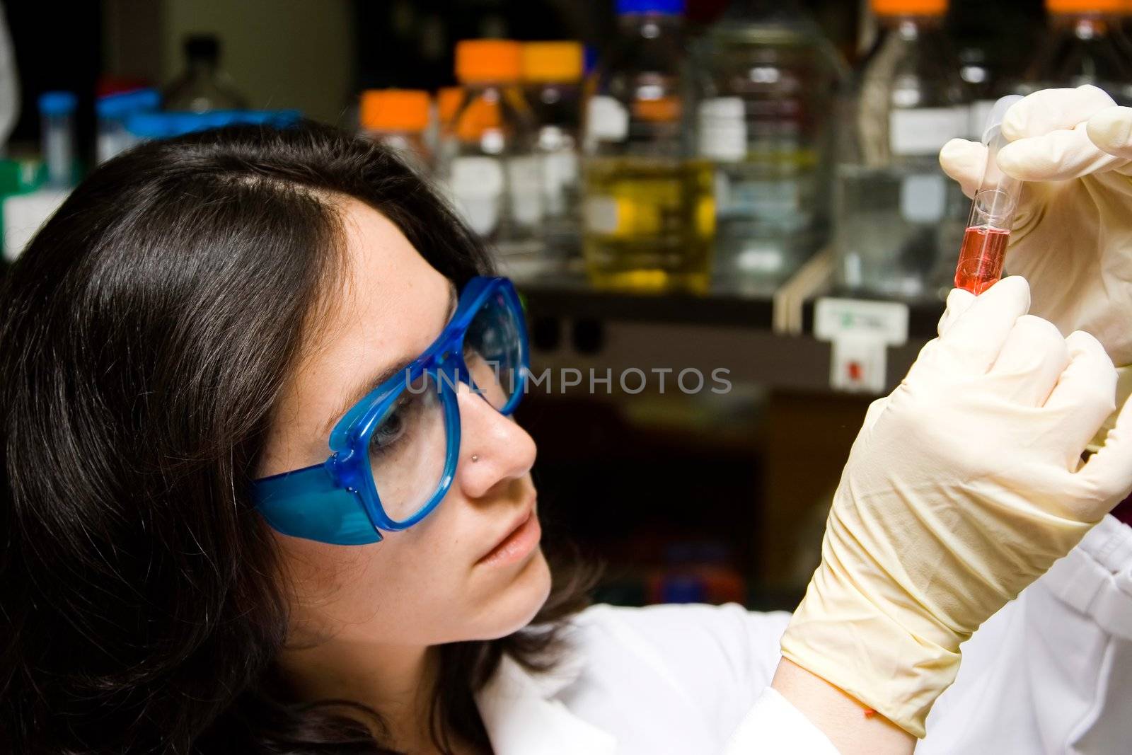 Scientist looking at test tube by phakimata