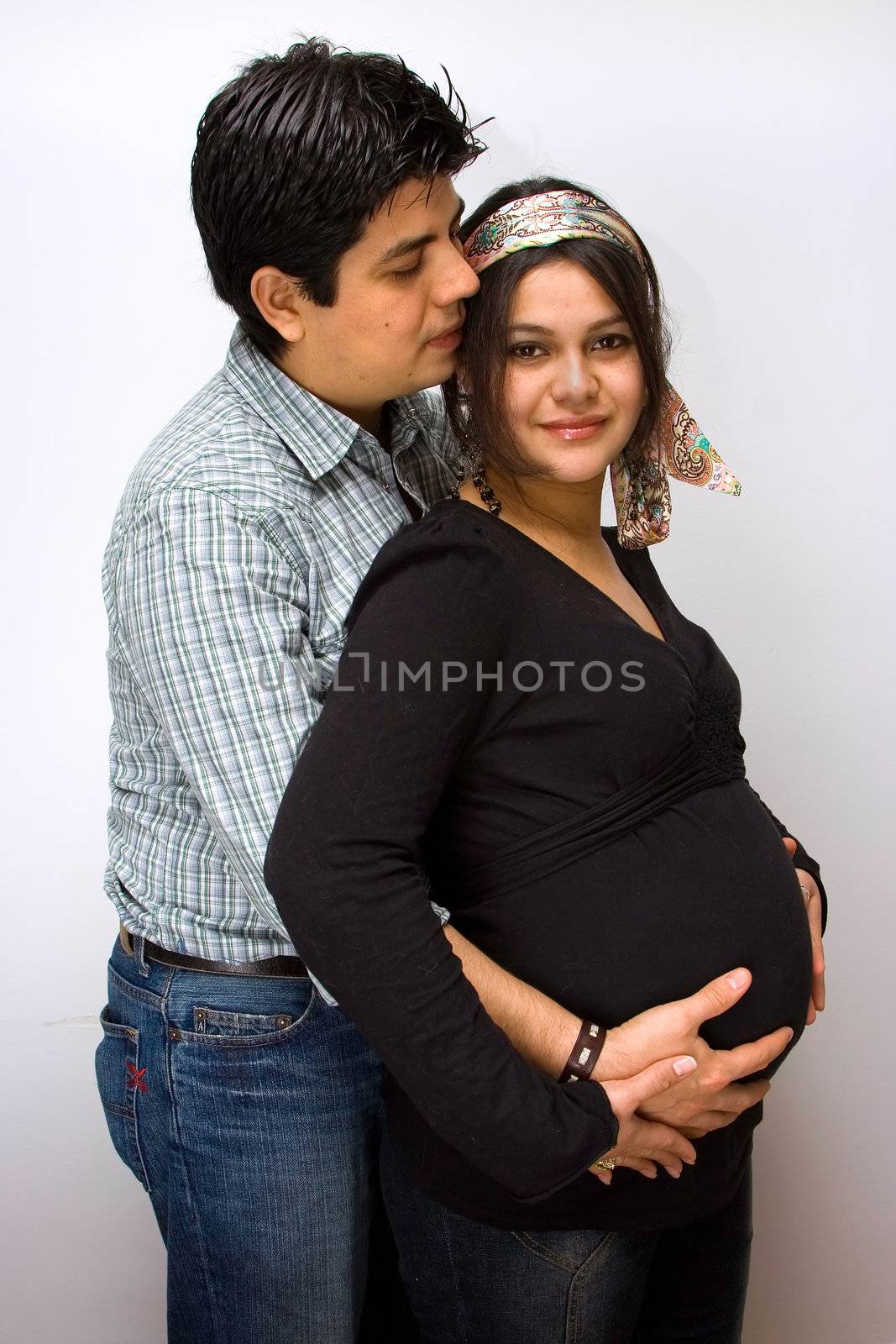 Parents expecting a baby. Father holds the belly of the mother and mother placed her hands on top of fathers hands.